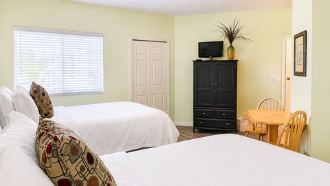 Bedroom sitting area with dresser storage, TV, small dining table, and plenty of natural light.