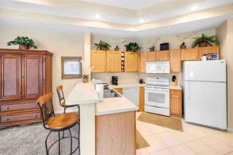 Fully equipped kitchen with cabinet storage, full-size appliances, breakfast bar seating, and an open view into the living space.