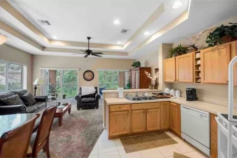 Open kitchen and living area featuring tray ceilings, full-size appliances, breakfast bar seating, and plenty of natural light.
