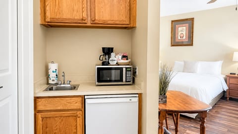 Convenient kitchenette area with sink, microwave, mini fridge, cabinet storage, and easy access to the bedroom.