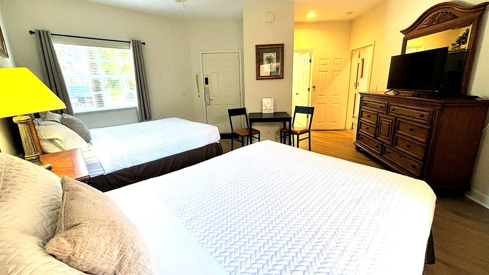 Spacious bedroom featuring two comfortable beds, dresser storage, TV, and plenty of natural light.