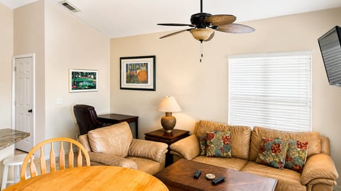 Bright living and dining area with cozy seating, ceiling fan, and a welcoming open layout.