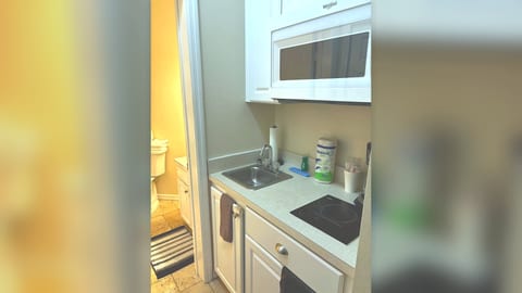 Convenient kitchenette area with sink, microwave, mini fridge, and easy access to the bathroom.