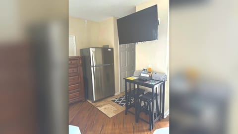 Bedroom sitting area with TV, dresser storage, mini fridge, and a small dining/work table.