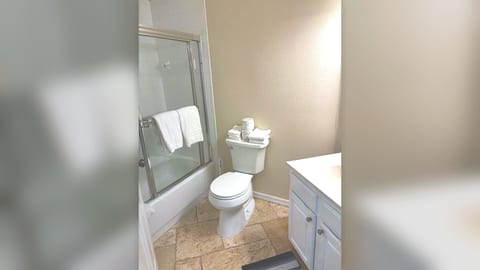 Clean bathroom with shower enclosure, toilet, tile flooring, and neutral finishes.