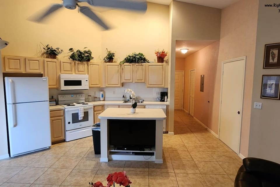 Open kitchen and living area with tile flooring, full-size appliances, breakfast bar, and easy access to the main hallway.