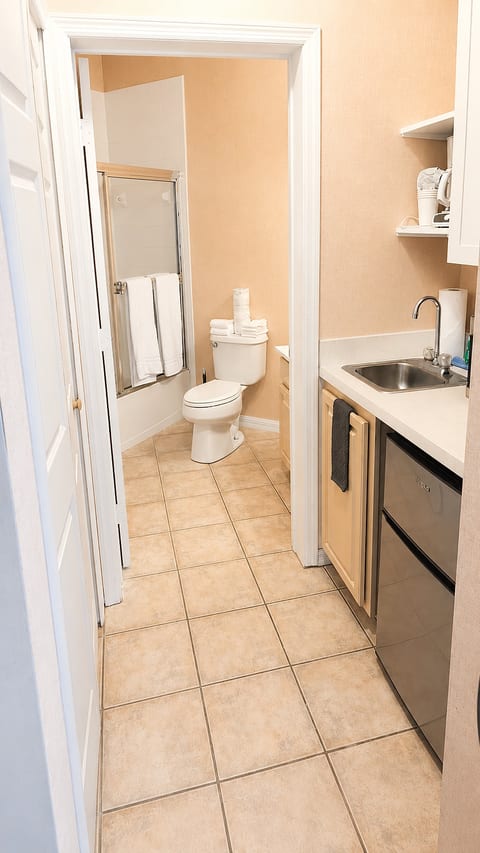 Functional kitchenette and bathroom area with tile flooring, shower access, and convenient in-room amenities.