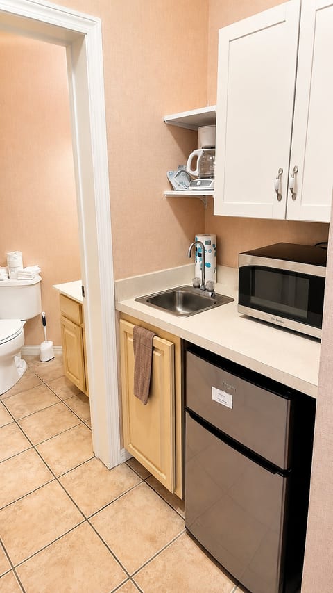 Convenient kitchenette area with sink, microwave, mini fridge, and easy access to the bathroom.