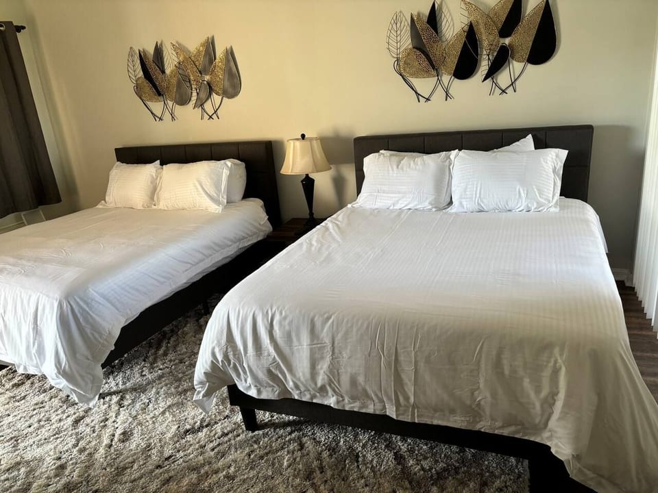 Spacious bedroom featuring two comfortable beds, dresser storage, and a bright, relaxing setup.