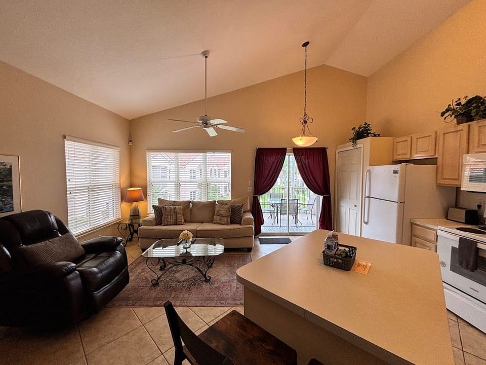 Open-concept living, dining, and kitchen area with comfortable seating, tile flooring, and plenty of natural light.