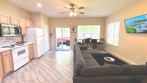 Bright open-concept kitchen and living area with wood-look flooring, comfortable seating, and easy access to the screened patio.