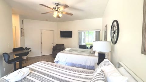 Spacious bedroom featuring two comfortable beds, ceiling fan, TV, and a bright, relaxing layout.