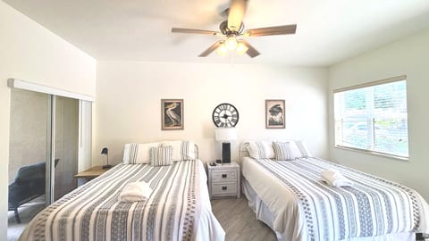 Comfortable bedroom with two beds, ceiling fan, closet space, and plenty of natural light.