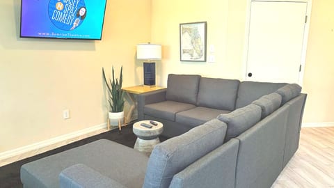 Cozy living room with large sectional seating, wall-mounted TV, and clean modern decor.