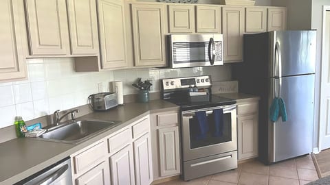 Updated kitchen featuring light cabinetry, stainless steel appliances, tile backsplash, and convenient counter space.