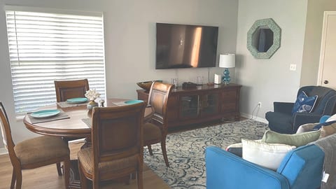 Spacious living area with dining space, TV console, cozy seating, and plenty of natural light.