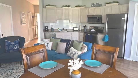 Open dining and kitchen area with a full dining table, light cabinetry, and a welcoming flow into the main living space.