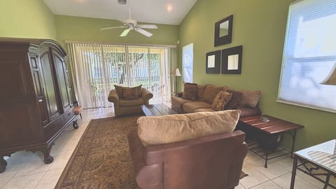 Relax in style! This spacious living room boasts high ceilings, comfortable plush seating, a large media armoire, and sliding glass doors that lead directly out to a peaceful screened lanai.