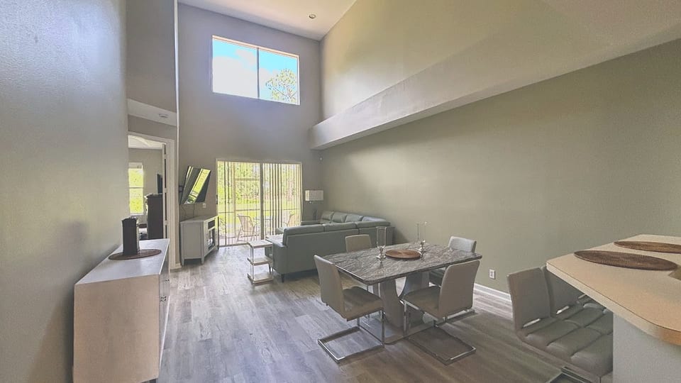 Welcome to a bright and expansive living space! This dramatic, two-story great room features beautiful wood-look flooring, neutral tones, and an open layout that effortlessly connects dining and lounging areas.