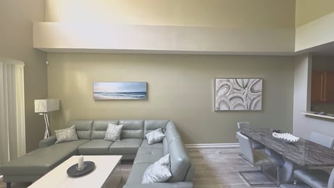 A perfectly styled conversation area showcasing soaring ceilings, elegant modern wall art, and an airy, uncluttered feel.