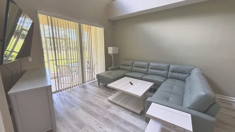 Natural light pours into the main living space through floor-to-ceiling glass doors, offering serene, leafy views of the outdoor landscape.