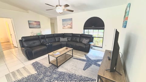 Cozy living room featuring a large sectional sofa, coffee table, arched window, and relaxed coastal decor.