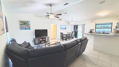 Open living, dining, and kitchen area with comfortable sectional seating, tile flooring, and a bright spacious layout.