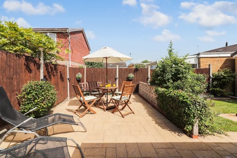 Sunny private patio sun trap with outdoor dining, parasol shade, loungers, and enclosed garden space