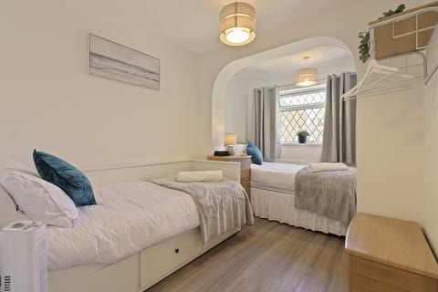 Bright twin bedroom with two single beds, storage, hanging space, and a cosy arched alcove layout