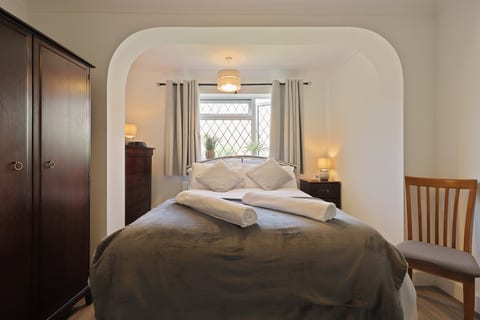 Comfortable double bedroom with fresh linens, warm lighting, wardrobe storage, and natural light