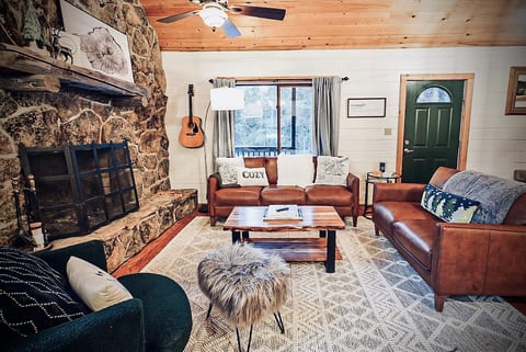 Kick back in the living area, complete with a cozy wood-burning moss rock fireplace, modern furnishings, and chic decor for the perfect mountain retreat ambiance.