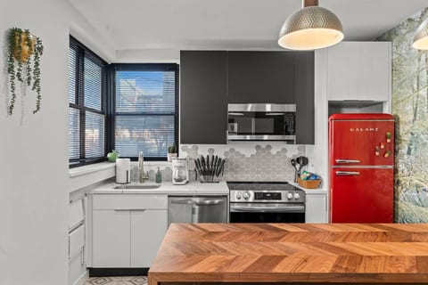 This stylish kitchen blends retro charm with modern conveniences. A bold red fridge, stainless appliances, and a bright backsplash make cooking a joy. Fully equipped and airy, it’s perfect for meals or morning coffee during your stay.