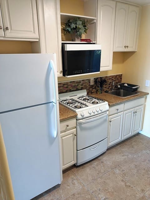 Full-size fridge with top freezer, gas stove and oven, and built-in microwave.