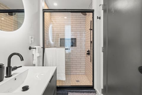 Spa-style bathroom with sleek black fixtures, lighted mirror, and minimalist design for a calming start or end to your day.
