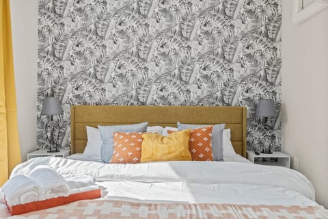 Cozy, colorful bedding and statement wallpaper create the perfect modern-meets-tropical hideaway.