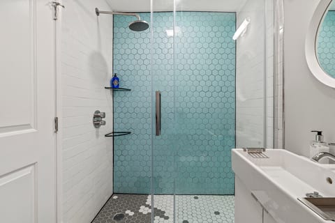 Enjoy a rejuvenating rinse in the rainfall shower framed by bold blue tile and modern glass doors.