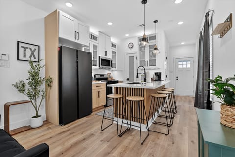 Modern chef’s kitchen with island seating, coffee bar & black appliances