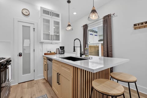 Modern kitchen with quartz peninsula, pendant lights, and coffee bar