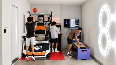 Private game room with arcade hoops, classic games, and neon style