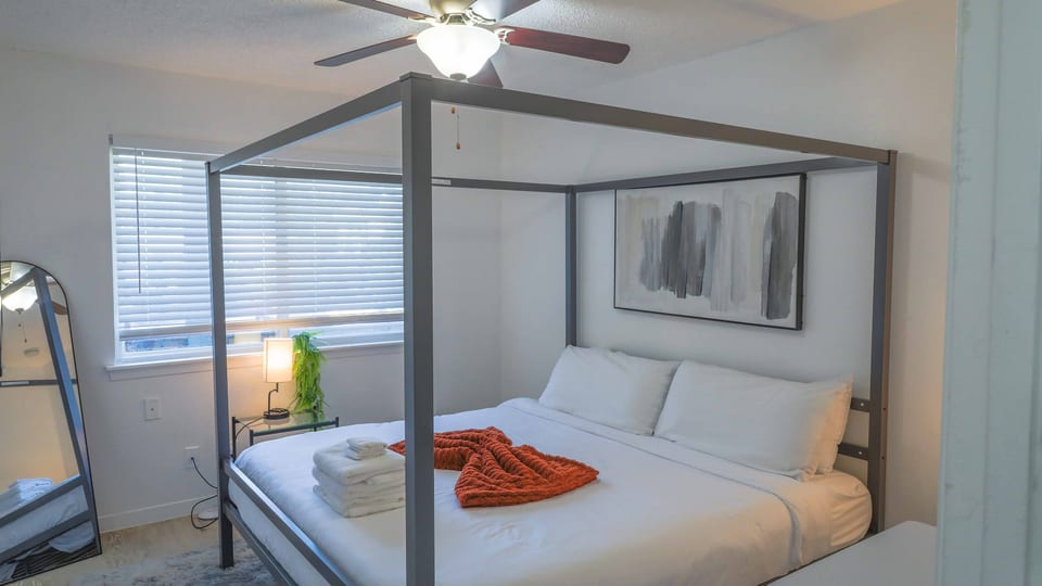 Bright modern bedroom with four-poster bed and cozy designer touches