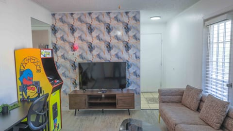 Cozy lounge with TV, natural light, and a fun retro arcade game