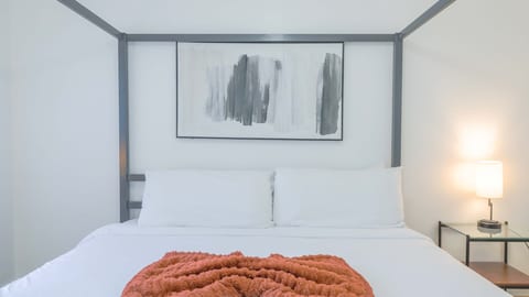 Bright modern king bedroom with cozy accents and soft bedside lighting