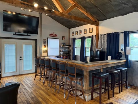 Rustic entertainment space with wraparound bar, TV, and plenty of seating
