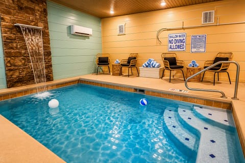 Private indoor pool with waterfall feature and cozy lounge seating