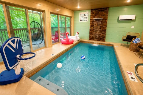 Private indoor pool with waterfall feature and peaceful wooded views