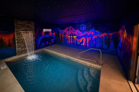 Private indoor pool with waterfall and striking mountain mural ambiance