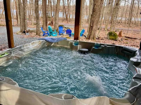 Six person hot tub, nestled under the deck, behind a beautiful mahogany privacy wall with seasonal lake views