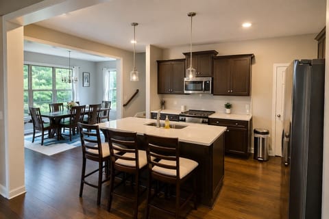 Spacious, fully equipped kitchen featuring a large island with seating, stainless steel appliances and plenty of counter space, opening directly to the bright dining area.