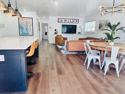 Bright open living area with dining space, bar seating, and large TV