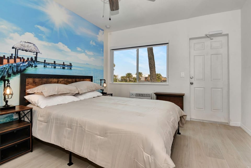 Queen bed with water scenery on wall and window.